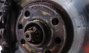 Nahaufnahme einer stark verrosteten und abgenutzten Bremsscheibe mit sichtbaren Spuren von Bremsstaub und Korrosion.