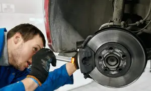 Mechaniker prüft Bremse, um zu beheben, dass das Lenkrad ruckelt beim Bremsen.