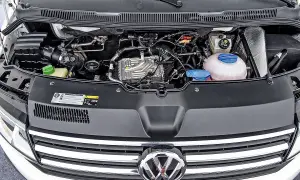 VW T6 150 PS Motorraum mit sichtbaren Leitungen und Kühlmittelbehälter. Mögliche Probleme am Motor sind hier zu sehen.