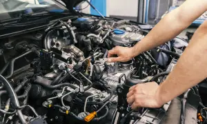 Mechaniker arbeitet am Motor eines Autos. Informieren Sie sich über die motorraum reinigen kosten, um Ihr Fahrzeug in Topform zu halten.