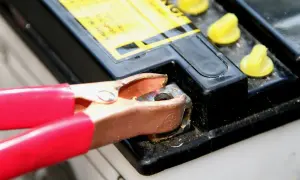 Rote Klemme verbindet sich mit einem Batteriepol, um eine tiefentladene Batterie wieder aufzuladen.