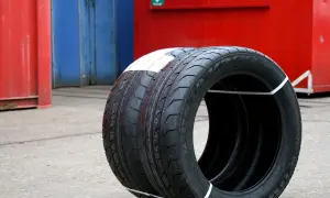 Zwei Kumho Wintercraft WP52 Reifen, bereit für den Test, stehen vor roten und blauen Containern.