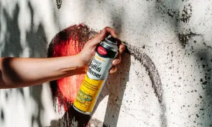 Hand hält Sprühdose mit Graffiti-Entferner. Ideal, um Graffiti von Wänden zu entfernen, fast wie felgenreiniger selber machen.