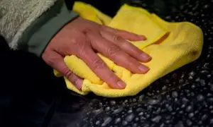 Hand poliert mit gelbem Tuch den dunklen Lack, um das Auto zu polieren und versiegeln.