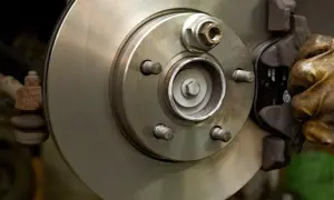 Hand in glove works on a car brake disc, ready to replace the bremsbelag.