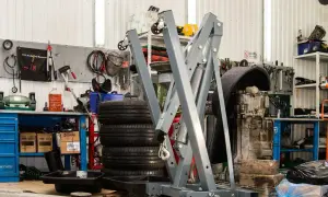 Geräte und Reifen in einer **freien Werkstatt**. Ein Motor hängt an einem Kran, Werkzeuge sind an der Wand befestigt.