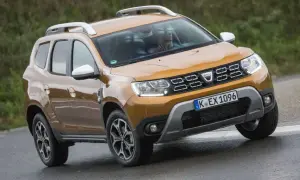 Ein oranger Dacia Duster fährt auf nasser Straße. Mögliche Dacia Duster Probleme sind hier nicht sichtbar.