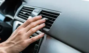 Hand prüft Lüftungsschlitze im Auto. Keine kühle Luft, wahrscheinlich ist der Klimakompressor defekt.