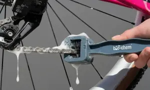 Mit einem speziellen Werkzeug wird die Fahrradkette gereinigt und gepflegt. Schaum tropft von der Kette.