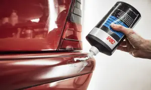 Hand trägt Politur auf roten Kotflügel auf, um klavierlack auto reinigen.