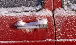Roter Autolack mit Schnee bedeckt. Wichtig: auto gummi pflegen winter, damit Türen nicht festfrieren.