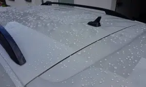 Wassertropfen perlen auf dem Dach eines Autos ab. Ein autoversiegelung test zeigt die wasserabweisende Wirkung.