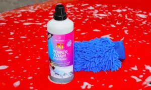 Flasche "A1 Power Foam Shampoo" und blauer Waschhandschuh auf rotem, seifigem Autolack. So gelingt das auto waschen ohne autoshampoo.