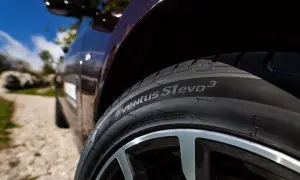 Nahaufnahme eines Hankook Ventus S1 evo 3 Reifens auf einem dunklen Auto, bereit für einen Test auf einer Schotterstraße.