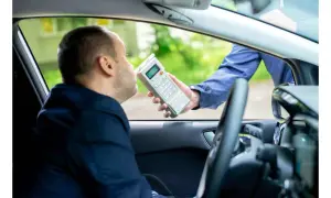 Polizist führt Atemalkoholtest durch. Mann im Auto bläst in Gerät, um die Promillegrenze beim Autofahren zu prüfen.