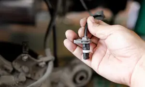 Hand hält ABS-Sensor. Defekter ABS-Sensor Symptome können durch Austausch behoben werden.