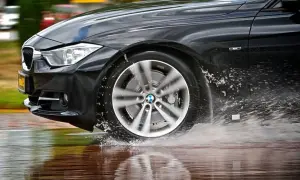 Schwarzer BMW fährt durch Wasserpfützen, was auf einen Uniroyal RainSport 5 Test hindeutet.