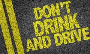 Gelbe Schrift auf Asphalt: "DON'T DRINK AND DRIVE". Informiert über die Promillegrenze Italien.