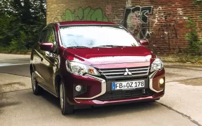 Roter Mitsubishi Space Star fährt auf einer Straße. Keine Anzeichen von mitsubishi space star krankheiten, nur ein Auto in Bewegung.