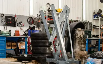 Geräte und Reifen in einer **freien Werkstatt**. Ein Motor hängt an einem Kran, Werkzeuge sind an der Wand befestigt.