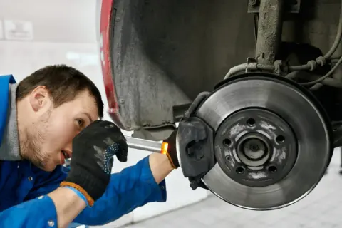 Mechaniker prüft Bremse, um zu beheben, dass das Lenkrad ruckelt beim Bremsen.