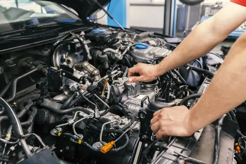 Mechaniker arbeitet am Motor eines Autos. Informieren Sie sich über die motorraum reinigen kosten, um Ihr Fahrzeug in Topform zu halten.