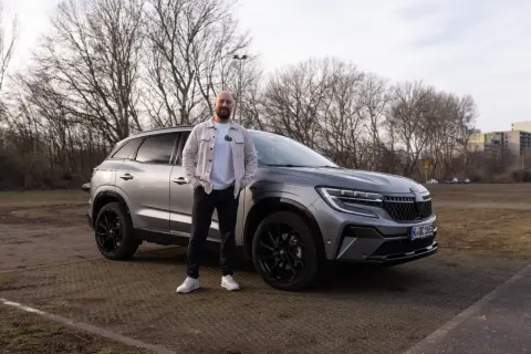 Mann steht neben grauem Renault Austral. Keine Probleme mit diesem Auto, nur ein toller Tag.