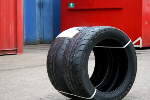 Zwei Kumho Wintercraft WP52 Reifen, bereit für den Test, stehen vor roten und blauen Containern.