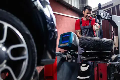 Mechaniker wechselt Reifen an einem BMW. Informieren Sie sich über die BMW Reifenwechsel Kosten.