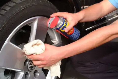 Hände reinigen Felgen mit einem Tuch und WD-40.
