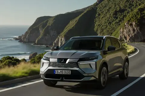 Grauer Mitsubishi Eclipse Cross fährt auf einer Küstenstraße. Keine Probleme mit diesem SUV, der die Landschaft genießt.