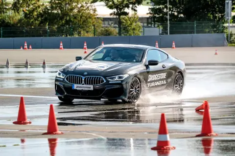 BMW fährt auf nasser Strecke, Wasser spritzt. Bridgestone Turanza 6 Test auf dem Prüfstand.