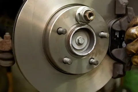 Hand in glove works on a car brake disc, ready to replace the bremsbelag.