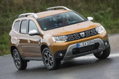 Ein oranger Dacia Duster fährt auf nasser Straße. Mögliche Dacia Duster Probleme sind hier nicht sichtbar.