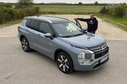 Mann lehnt am neuen Mitsubishi Outlander. Keine Probleme hier, nur ein schöner SUV.