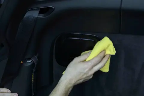Hand poliert matten Kunststoff im Auto mit gelbem Tuch.