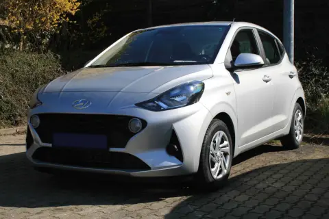 Silberner Hyundai i10, der auf einem gepflasterten Weg steht. Ein Blick auf die Frontpartie, die typische Hyundai i10 Krankheiten wie Rost an den Radläufen oder Probleme mit dem Getriebe vermeiden sollte.