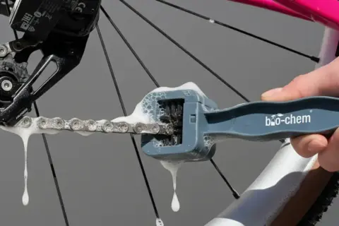Mit einem speziellen Werkzeug wird die Fahrradkette gereinigt und gepflegt. Schaum tropft von der Kette.