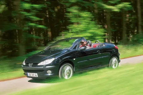 Schwarzer Peugeot 206 CC fährt offen durch grünen Wald. Bekannte peugeot 206 cc schwachstellen sind hier nicht sichtbar.