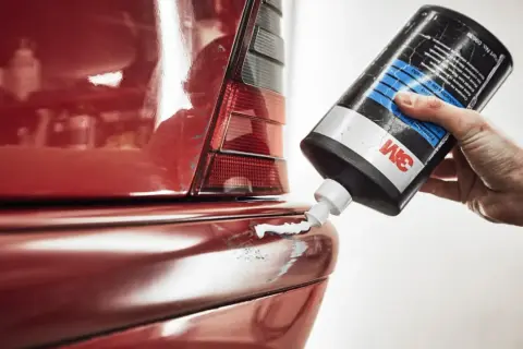 Hand trägt Politur auf roten Kotflügel auf, um klavierlack auto reinigen.