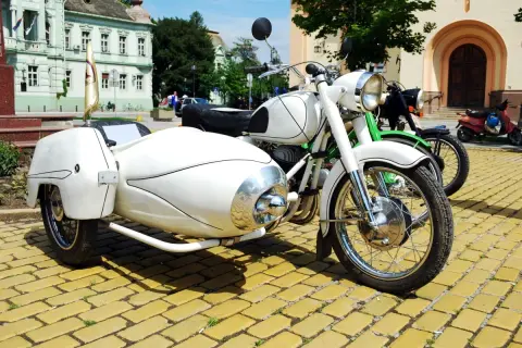 Weiße Motorräder mit Beiwagen und Roller stehen auf einem gelben Kopfsteinpflaster. Ein Helm liegt auf dem Roller, um die Strafe für Fahren ohne Helm zu vermeiden.