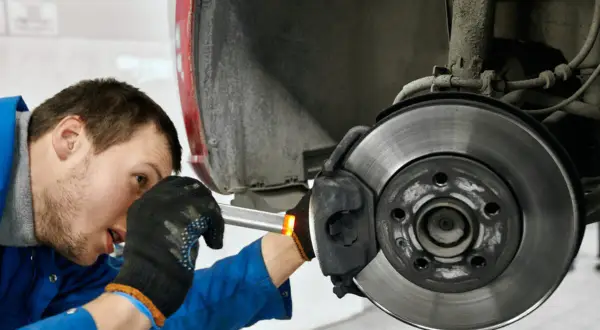 Mechaniker prüft Bremse, um zu beheben, dass das Lenkrad ruckelt beim Bremsen.