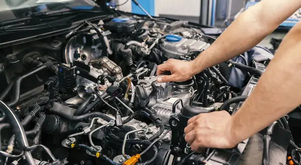 Mechaniker arbeitet am Motor eines Autos. Informieren Sie sich über die motorraum reinigen kosten, um Ihr Fahrzeug in Topform zu halten.