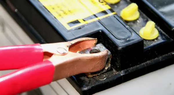 Rote Klemme verbindet sich mit einem Batteriepol, um eine tiefentladene Batterie wieder aufzuladen.