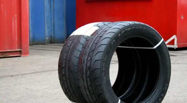Zwei Kumho Wintercraft WP52 Reifen, bereit für den Test, stehen vor roten und blauen Containern.
