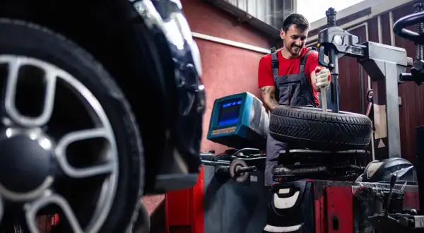 Mechaniker wechselt Reifen an einem BMW. Informieren Sie sich über die BMW Reifenwechsel Kosten.