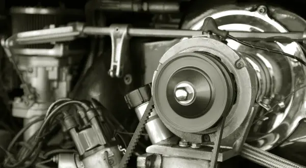 Nahaufnahme eines Motors, bei dem der Keilriemen gerissen ist. Ein Zahnriemen liegt lose um eine Riemenscheibe.
