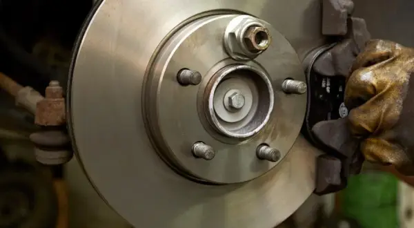 Hand in glove works on a car brake disc, ready to replace the bremsbelag.