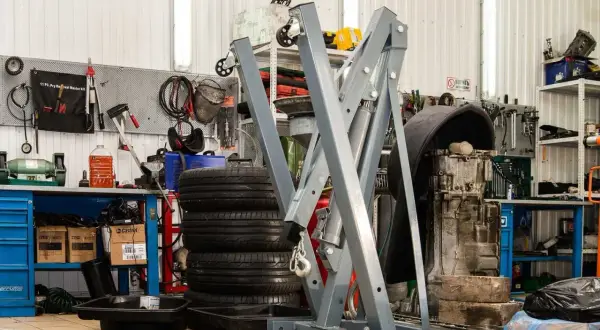Geräte und Reifen in einer **freien Werkstatt**. Ein Motor hängt an einem Kran, Werkzeuge sind an der Wand befestigt.