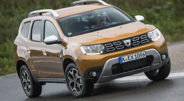 Ein oranger Dacia Duster fährt auf nasser Straße. Mögliche Dacia Duster Probleme sind hier nicht sichtbar.